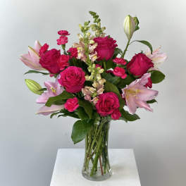 Pink roses and lilies arranged in a clear glass vase