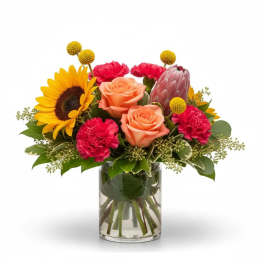Bouquet of sunflowers, peach roses, and pink carnations in a glass vase
