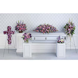 Funeral casket surrounded by pink and purple floral sprays