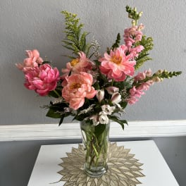 Pink and peach flowers arranged in a clear glass vase