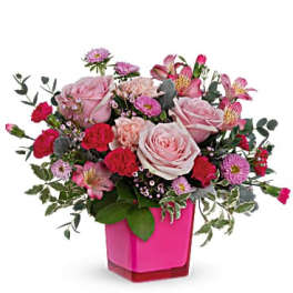 Pink and red mixed flower arrangement in a bright pink vase