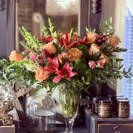 Mixed bouquet of peach roses and pink lilies in a clear glass vase