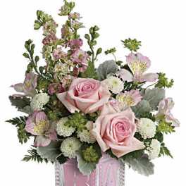 Pink roses and mixed blooms arranged in a clear glass cube vase