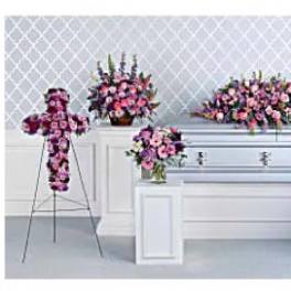 Casket surrounded by pink and purple floral sprays on stands