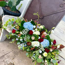 Large mixed bouquet with blue hydrangeas, red roses, and white blooms