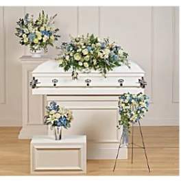 White casket with blue and white floral sprays in a funeral room