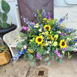 Large mixed bouquet with sunflowers and blue-purple flowers on a bench