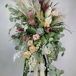 Tall floral standing spray with peach roses, protea, and eucalyptus