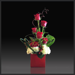 Tall red rose arrangement in a red square vase