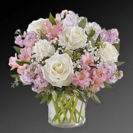 Pink and white bouquet of roses and lilies in a clear glass vase