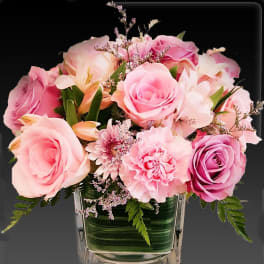 Pink roses and carnations in a clear square vase