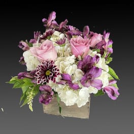 Pink roses and white hydrangeas with purple flowers in a square container