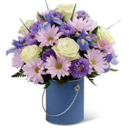 Bouquet of pastel flowers in a blue bucket vase