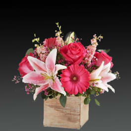Pink roses and lilies arranged in a wooden box