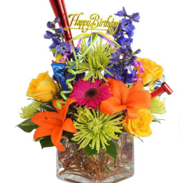 Colorful birthday bouquet in a glass vase with a "Happy Birthday" topper