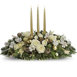 White roses and greenery arranged with three gold candles