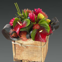 Tropical floral arrangement in a wooden box with red anthuriums and pink blooms