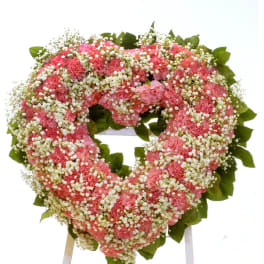 Heart-shaped pink floral wreath on a stand