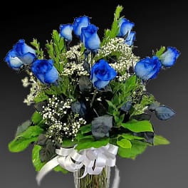 Blue roses in a clear glass vase with white filler flowers