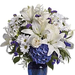 White lilies and daisies with blue flowers in a blue vase