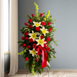 Standing floral spray with red roses, white lilies, and a red ribbon