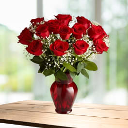 Red roses arranged in a red glass vase