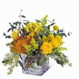 Yellow floral arrangement in a clear square glass vase