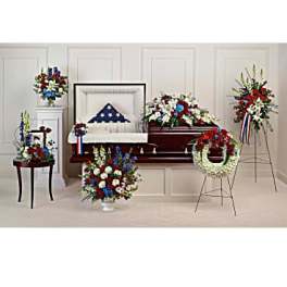 Patriotic funeral floral set with red, white, and blue arrangements around a casket