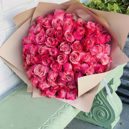 Large bouquet of bright pink roses wrapped in tan paper