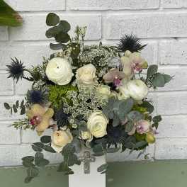 White floral arrangement in a square vase with a cross ornament
