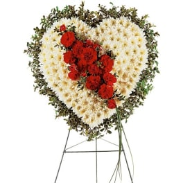 Heart-shaped funeral spray of white and red flowers on a stand