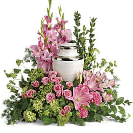 Pink lilies and roses arranged around a white urn
