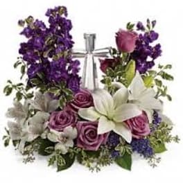 Purple and pink floral arrangement with white lilies and roses in a clear vase