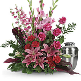 Pink lilies and roses arranged beside a silver urn