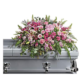 Pink and white casket spray of roses and lilies arranged on a silver casket