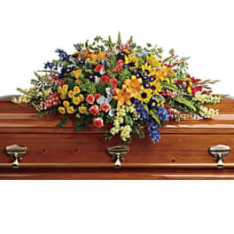 Large colorful floral spray on a wooden casket