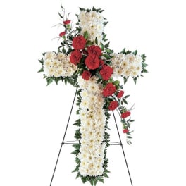 Cross-shaped floral funeral spray with white and red flowers on an easel