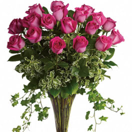 Pink roses arranged in a clear glass vase with trailing ivy