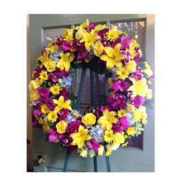 Large yellow and purple floral wreath on a stand