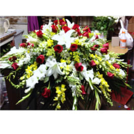 Large floral spray with red roses, white lilies, and yellow flowers
