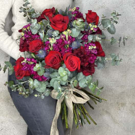 Hand-tied bouquet of red roses and magenta flowers with eucalyptus
