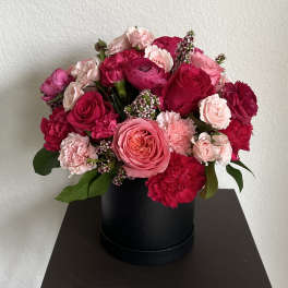 Pink and red rose and carnation arrangement in a black hat box