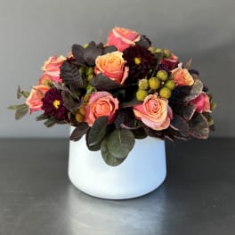 Pink and peach roses arranged in a white vase