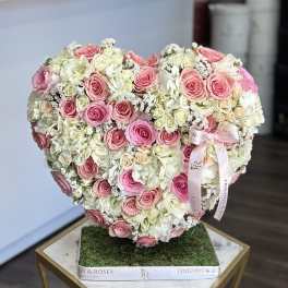 Heart-shaped arrangement of pink and white roses on a square base