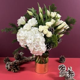 White floral arrangement in a copper vase with pinecones and evergreen branches