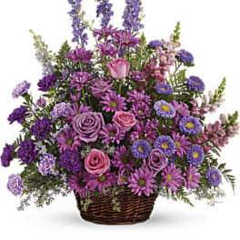 Purple and pink mixed flower arrangement in a wicker basket