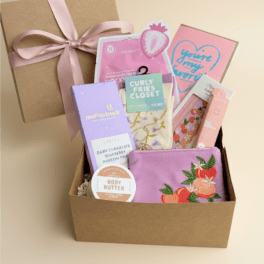 Gift box with assorted beauty items and a pink ribbon