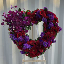 Heart-shaped floral wreath with purple orchids, red gerberas, and chrysanthemums
