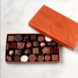 Open box of assorted chocolates with an orange lid