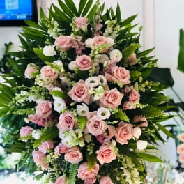 Large standing spray of pink roses and white blooms with greenery